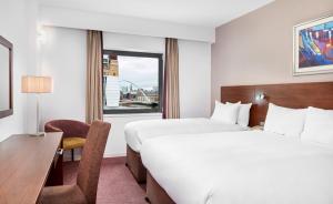 een hotelkamer met 2 bedden, een bureau en een raam bij Leonardo Hotel Newcastle Quayside in Newcastle upon Tyne