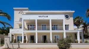 um edifício branco na praia com palmeiras em Hotel Nautilus em Cagliari