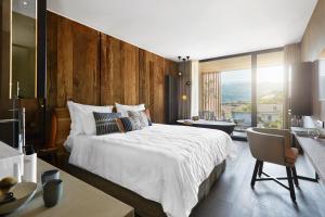 a bedroom with a large white bed and a desk at Hotel Löwenhof in Bressanone