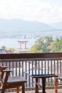 een tafel en banken op een balkon met uitzicht bij Kikunoya in Miyajima