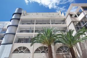 un edificio blanco con palmeras delante en Odalys City Beausoleil les Hauts de la Principauté, en Beausoleil