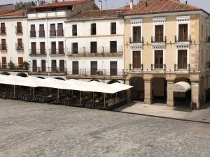 een rij witte paraplu's voor gebouwen bij Apartamentos Soho Boutique Plaza Mayor Caceres in Cáceres