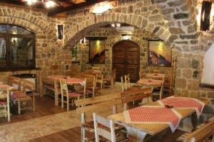 un restaurant avec des tables et des chaises et un mur en pierre dans l'établissement Stara Hercegovina, à Trebinje