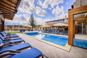 einen Pool mit blauen Liegestühlen neben einem Gebäude in der Unterkunft Katarino SPA Hotel in Bansko