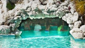 un groupe de personnes assis dans une piscine dans une grotte de rochers dans l'établissement The Marlin at Taino Beach Resort, à Freeport