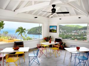 ein Restaurant mit Tischen und Stühlen und Meerblick in der Unterkunft Le Panoramic in Les Trois-Îlets