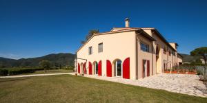 a large white and red building with a grass yard at Cascina Canova B&B in San Giuliano Terme