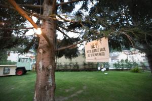 a sign on a tree in a yard at Ostello Alpino in Bormio