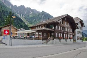 un edificio sul lato di una strada con montagne di Hotel Bären Guttannen a Guttannen