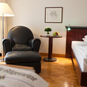 a room with a chair and a table and a bed at Grand Hotel Mussmann in Hannover