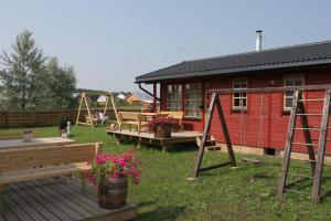 un patio con bancos y una casa con parque infantil en Love Island Guesthouse, en Druskininkai