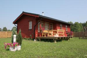 una casa roja con una terraza y sillas delante de ella en Love Island Guesthouse, en Druskininkai