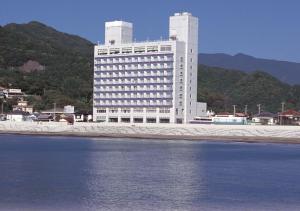 - un grand bâtiment blanc situé à côté d'une étendue d'eau dans l'établissement Nishiizu Matsuzaki Itoen Hotel, à Matsuzaki