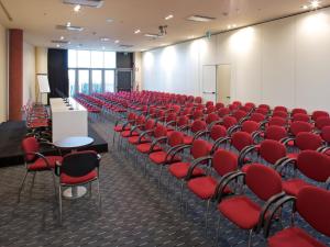 an empty room with red chairs and a podium at Grand Hotel Mattei in Ravenna