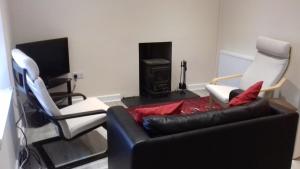 a living room with a couch and two chairs and a fireplace at Highfield Cottage in Kirknewton