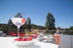 un verre de vin assis sur une table avec un bol de fraises dans l'établissement Thomar Boutique Hotel, à Tomar