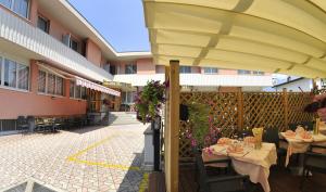 een patio met tafels en een grote parasol bij Hotel Vela in Trento