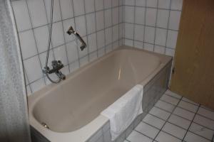 a white bath tub in a white tiled bathroom at Ferienwohnungen Goldbach 1. Stock in Regensburg