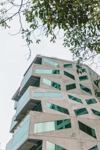 un grand bâtiment avec des fenêtres en verre sur son côté dans l'établissement Janevalla Bandung, à Bandung