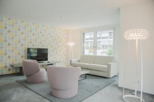 - un salon avec un canapé, des chaises et une télévision dans l'établissement Apartment JungfrauCenter Brienzersee - GRIWA RENT AG, à Interlaken