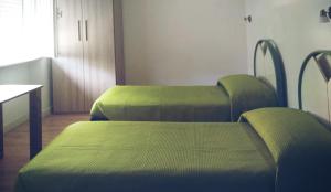 two green beds in a room with a table at Cà della Roggia in Rovereto