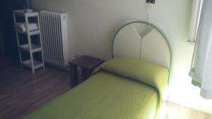 a small bedroom with a green bed and a table at Cà della Roggia in Rovereto