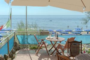 patio ze stołem i krzesłami oraz oceanem w obiekcie Hotel Villa Lo Scoglietto w mieście San Vincenzo