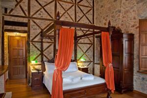 a bedroom with a canopy bed with orange curtains at Archontiko Hatzipanayioti in Leonidion