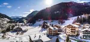 ein schneebedecktes Dorf mit Bergen im Hintergrund in der Unterkunft Garni Rives in St. Ulrich in Gröden