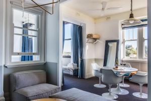 een woonkamer met een tafel, stoelen en ramen bij Hotel Palisade in Sydney