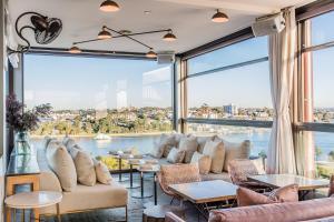 een kamer met een groot raam met banken en tafels bij Hotel Palisade in Sydney