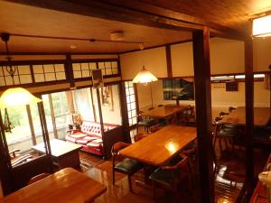 een eetkamer met houten tafels en stoelen bij Yufuin Country Road Youth Hostel in Yufu