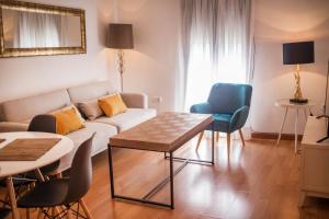 een woonkamer met een bank en een tafel en stoelen bij Apartamentos Soho Boutique Plaza Mayor Caceres in Cáceres