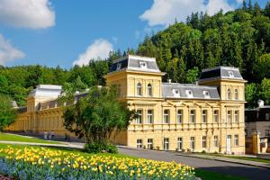 un gran edificio amarillo con flores delante en Ensana Centrální Lázně - Maria Spa, en Mariánské Lázně