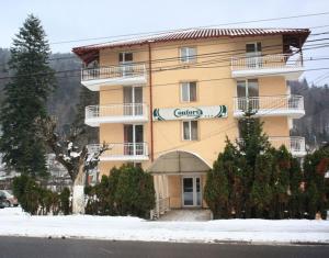 um grande edifício amarelo com um guarda-chuva na neve em Pensiunea Confort em Buşteni