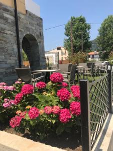 un jardín con flores rosas, mesas y sillas en Anthelia, en Skala Potamias