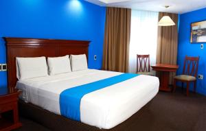 een hotelkamer met een groot bed met blauwe muren bij Hotel Lois Veracruz in Veracruz