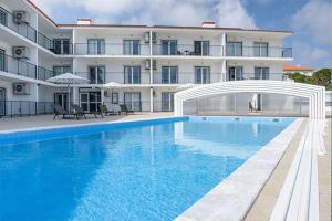 a hotel with a swimming pool in front of a building at Cerca da Vitoria 3 Milfontes in Vila Nova de Milfontes