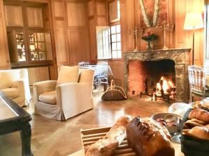 sala de estar con chimenea y mesa con pan en Château de la Cour Senlisse, en Senlisse