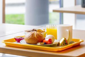 - un plateau avec une assiette de nourriture et une tasse de jus d'orange dans l'établissement T3 Budget Zwickau, à Zwickau