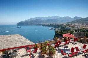 uma vista para uma massa de água com mesas e cadeiras em Hotel Minerva em Sorrento