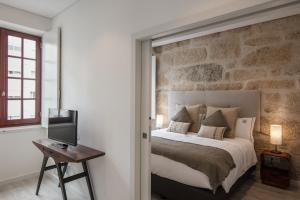 een slaapkamer met een bed met een stenen muur bij Porto Deluxe Suites in Porto