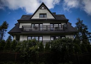 a house with a balcony on top of a fence at Willa Pod Lasem in Kościelisko