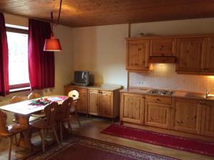 una cocina con armarios de madera y una mesa con comedor. en Residenze Sonnenschein Casa Bianca, en Villabassa