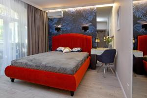 een slaapkamer met een rood bed en een bureau bij City Garden Apartments in Odessa