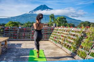 une femme debout sur un tapis de yoga avec une montagne en arrière-plan dans l'établissement The Purpose Hostel, à Antigua Guatemala