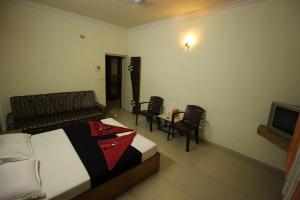 a bedroom with a bed and chairs and a television at Hotel Laxmibai Palace in Shirdi