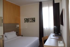 una camera con letto e scrivania con TV di Hotel First a Calenzano