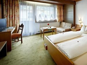 a bedroom with a bed and a desk and a couch at Landhotel Kaserer in Bramberg am Wildkogel