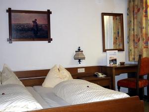 a bedroom with a bed and a desk and a mirror at Landhotel Kaserer in Bramberg am Wildkogel